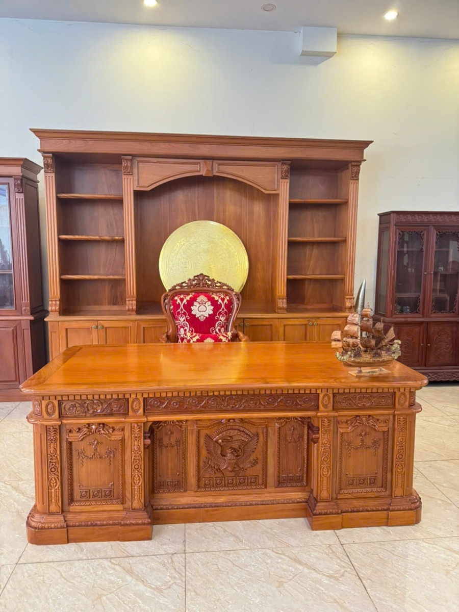 Ghế lãnh đạo nữ gỗ gõ đỏ bọc vải đỏ hoa văn vàng mang phong cách cổ điển sang trọng. Khung gỗ màu nâu đỏ kết hợp đệm và tựa lưng bọc vải hoa văn tinh tế, phù hợp với phòng làm việc giám đốc nữ và không gian nội thất văn phòng cao cấp. Sản phẩm được giới thiệu tại Gomynghe.